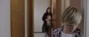 Le petit garçon blond du film Jusqu'à la garde de Xavier Legrand, dans le couloir de chez lui, tête baissée.