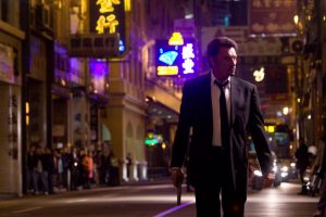 Johnny Hallyday acteur en costume-cravate, dans les rues de Hong Kong le revolver au poing, pour Vengeance.