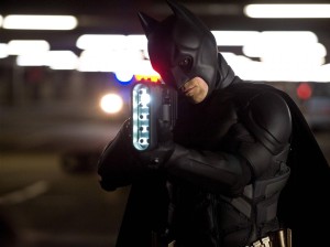 Batman pointe son arme à canon rectangulaire vers un malfrat dans le film The Dark Knight Rises, pour notre article sur le gadget dans le film d'espionnage.