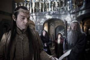Elrond, au premier plan, lit une feuille à Bilbo et Gandalf, à l'arrière plan, dans le film Le hobbit un voyage inattendu.