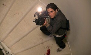 Lou dans un escalier tâché de sang braque sa caméra sur le plafond dans le film Night Call.