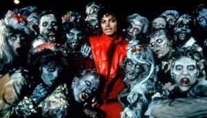 Michael Jackson en tenue rouge et noire pose au milieu de zombies pour le tournage d'un des clips réalisés par John Landis, Thriller.