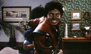 Michael Jackson se tourne vers la caméra avec ses yeux jaunes tandis qu'il mène sa copine vers l'extérieur du salon où ils se trouvent ; plan issu d'un des clips réalisés par John Landis, Thriller.