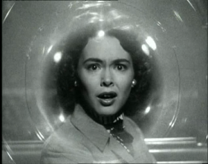 Le visage d'une femme effrayée, en noir et blanc, vue à travers ce qui semble être une spirale de verre ; plan issu du film Le météore de la nuit.