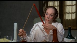 Donal Sutherland grimé en Casanova, assis à une table devant plusieurs verres et bouteilles vides dans le film Le Casanova de Fellini.