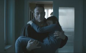 Jean-Claude Van Damne porte une adolescente dans ses bras, le long d'un couloir sombre, dans le film Lukas.