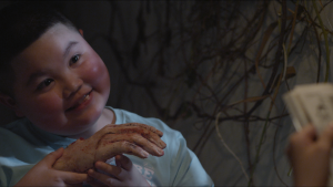 Un jeune garçon s'apprête à dévorer une main humaine, tout sourire, scène du film KFC.