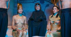 Jean-Pierre Léaud en mage noir, entouré de deux servantes seins nues, vêtues à l'égyptienne, scène du film Alien Crystal Palace pour notre critique.