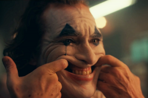 Joaquin Phoenix tire sa bouche avec ses doigts face au miroir pour simuler un sourire dans le film Joker pour notre article sur le cinéma sous Donald Trump.