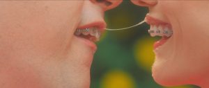 Un filet de bave lie deux bouches d'adolescentes avec des bagues sur les dents, scène du film Greener Grass pour notre interview de Dawn Luebbe et Jocelyn DeBoer.