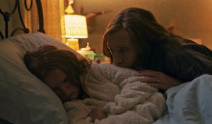 Toni Collette, inquiète, borde sa fille dans le film Hérédité.