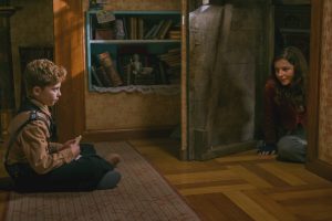 Jojo fait face à la jeune fille juive qu'il héberge, tous deux sont assis par terre, dans la maison de Jojo, une distance les sépare,  scène du film Jojo Rabbit.