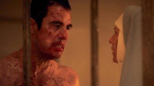 Dracula torse nu et éclaboussé de sang face à une nonne qui le regarde droit dans les yeux, scène de la mini-série Netflix Dracula.