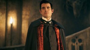 Le Comte Dracula, sur les marches de l'escalier de son château, avec sa fameuse cape noire et rouge, mais sous apparence humaine.