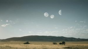 Plaine de montagne de jour, avec trois lunes dans le ciel, paysage du film The Endless.