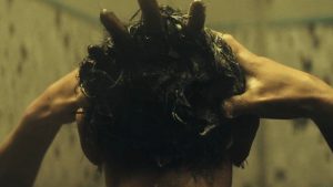 Une main de fantome sort des cheveux d'un homme sous la douche.