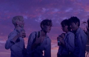 Quatre jeunes garçons en chemise blanche, s'enlacent, sur fond d'un ciel aux teintes roses et violettes dans le film Les garçons sauvages pour notre interview de Bertrand Mandico.