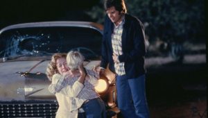 Billy fonce dans les bras de sa mère apeurée, son beau-père, debout, regarde les deux autres avec émotion, scène de nuit dans le film La vallée de la mort.