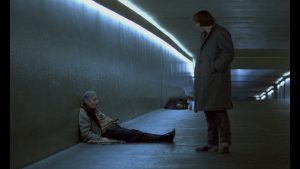 Gérard Depardieu debout face à un pauvre homme avachi par terre, dans un long tunnel, scène de nuit dans le film Buffet Froid.