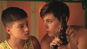 Un jeune mafieux montre à son petit frère comment on recharge un revolver, scène du film Piranhas.