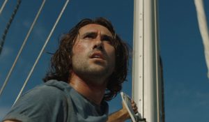 L'acteur Joe Azzopardi sur le voilier, scrute l'horizon inquiet en contre-plongée, scène du film The Boat.