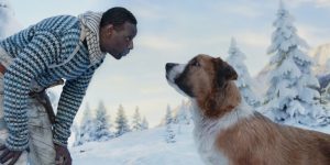 Omar Sy se penche vers le chien Buck dans un paysage enneigé, scène du film L'appel de la forêt.