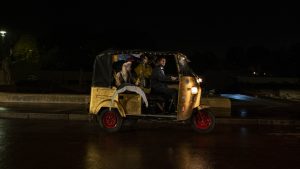 Trois personnages sont dans un rickshaw, un taxi à trois roues, roulant sur un pont de Paris de nuit, scène du film Une sirène à Paris.