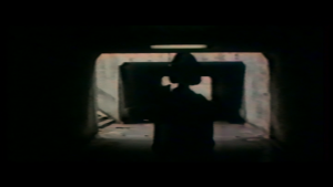 Une silhouette féminine en contre-jour s'avance dans un tunnel sombre, scène du film L'enfer des armes.