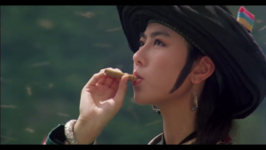 Une jeune femme asiatique avec un chapeau un biscuit près des lèvres qu'elle tient comme un cigare, scène d'un film de Tsui Hark pour notre analyse de filmographie.