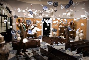 Deux hommes en costume se font face dans une vaissellerie dont les assiettes volent en éclats en l'air, scène du film Cloud Atlas.