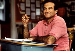 Jack (Robin Williams) à sa table d'écolier, un crayon à la main, écoute attentivement le cours.
