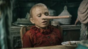 Alors qu'il est à table, le nez de Pinocchio s'allonge, scène du film de Matteo Garrone.