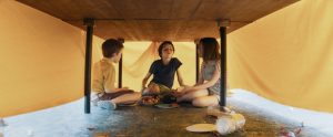 Les trois personnages de La dernière vie de Simon jouent sous une table qu'ils ont érigée en cabane cachés par la nappe.