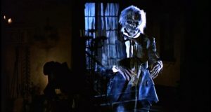Un fantôme squelettique effrayant, en costume de ville du XVIIIème siècle, devant une fenêtre que l'on voit à travers son corps transparent, scène du film Hell Night.