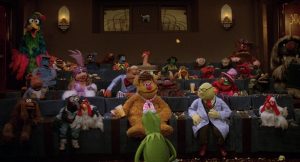Tous les Muppets réunis dans une salle de projection, face à Kermit qui s'adresse à eux, scène du film Les Muppets, ça c'est du cinéma.