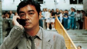 L'inspecteur Pao le téléphone portable à l'oreille tandis qu'une foule s'agglutine à quelques mètres derrière lui, en haut d'un escalier, scène du film Full Alert.