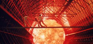 Trois silhouettes sur une passerelle, dans un tunnel spatial, tentent de fuir une boule de feu gigantesque, scène du film Le trou noir. 