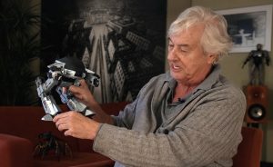 Paul Verhoeven, dans son bureau, montre une maquette de robot issue du film Robocop et conçue par Phil Tippett.