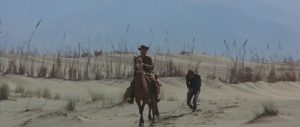 Brian Kelly sur son cheval tire Fabrizio Moroni relié par une corde les mains liées, scène dans le désert du film Tire, Django, tire.