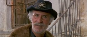 Plan rapproché-épaule sur le Major Charlie Donnegan avec son chapeau de vétéran et sa barbe grisonnante dans le film Tire, Django, Tire.