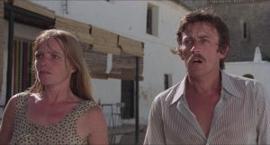 Le couple en vacances héros du film Les révoltés de l'an 2000 regardent, hors-champ, quelque chose qui les inquiète, dans une des rues désertes de l'île.