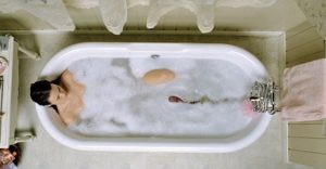 Une femme nue dans une baignoire, tandis qu'un grand ver surgit de sous l'eau, plan en plongée du film Horribilis.