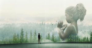 Une silhouette, qui paraît minuscule, est debout face à une immense image représentant un paysage de brume au dessus d'une forêt, une petite fille aux mains liées se dessine dans les nuages, scène de la mini-série Devs.