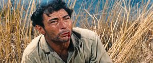 Lee Van Cleef suupliant, la lèvre au sang, à terre au milieu d'un champ de blé, scène du film Bravados.