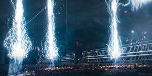 Sur un pont, un homme est agenouillé entre trois éclairs rectilignes qui fondent droit sur le bitume, scène de nuit dans le film Mortal.