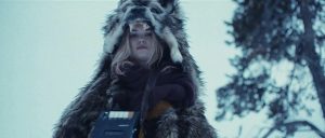 Sous un ciel blanc, une jeune femme blonde se tient debout, elle est couverte d'une peau d'ours, scène du film Starfish.
