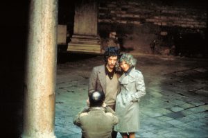 Le couple Julie Christie et Donald Sutherland pose devant un photgraphe près de colonnes venitiennes dans le film Ne vous retournez pas.