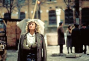 Julie Christie dans les rues de Venise, regarde en l'air les bras croisés, au fond à droite, un groupe de passants discute, scène du film Ne vous retournez pas.