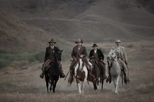 Les quatre héros de Bone Tomahawk cavalent à cheval dans une plaine montagneuse, peu de temps avant la nuit.