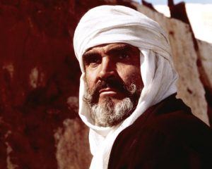 Gros plan sur le visage de Sean Connery dans le désert, le visage entouré d'un turban blanc dans le film Le lion et le vent.
